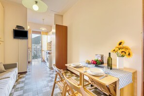 Un coin repas avec une table dressée pour deux personnes, un canapé et un téléviseur fixé au mur.