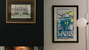 Une cheminée surmontée d’un tableau encadré et sous laquelle se trouve un autre tableau.