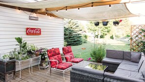 Une terrasse extérieure agrémentée d’une enseigne Coca-Cola, de sièges et de plantes en pot.