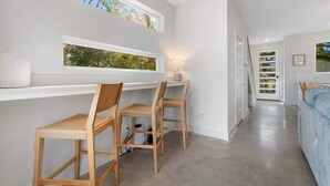 Una habitación moderna con escritorio, dos sillas, una cama y una escalera.