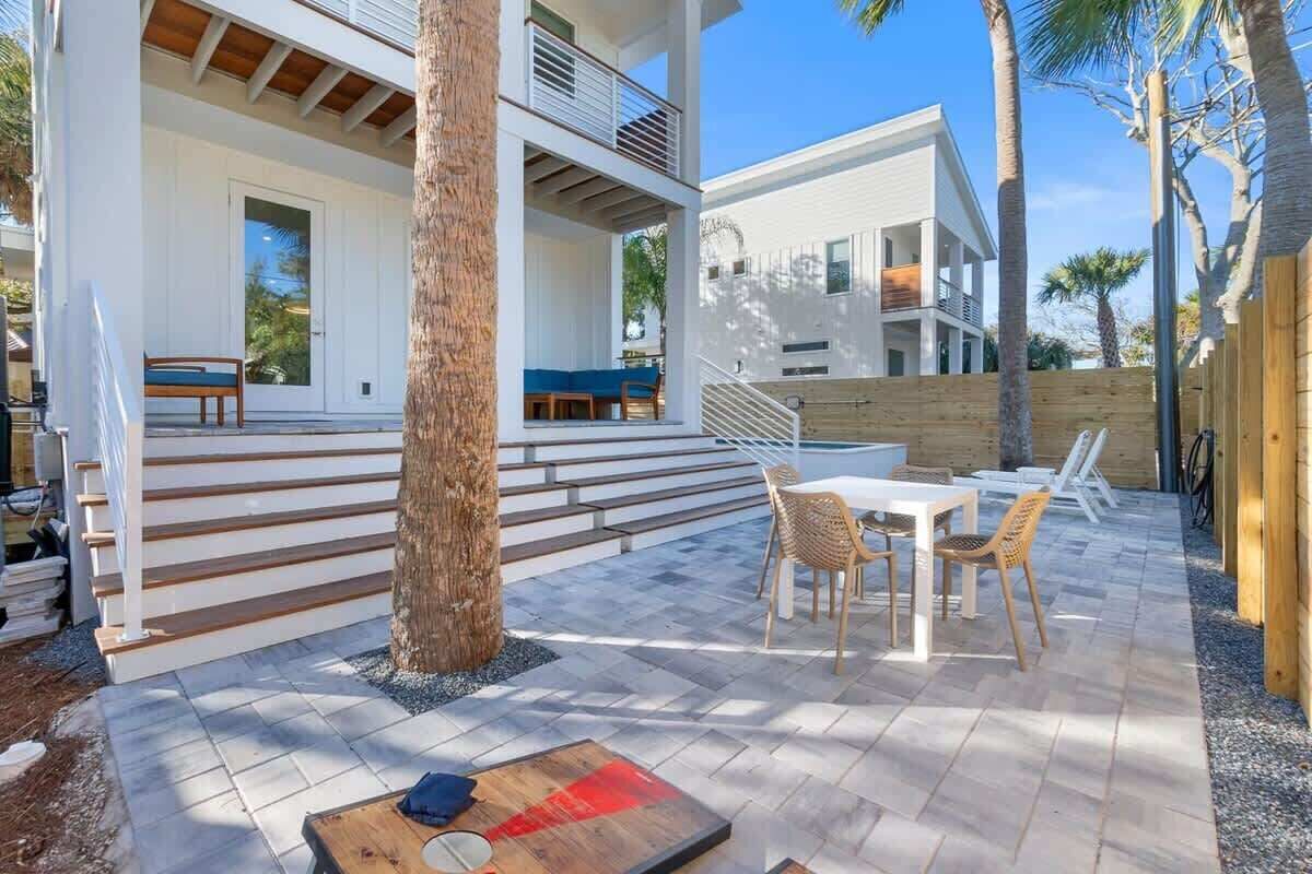 Une maison moderne dotée d’un patio couvert, d’un espace salon extérieur et d’un escalier menant à l’étage supérieur.