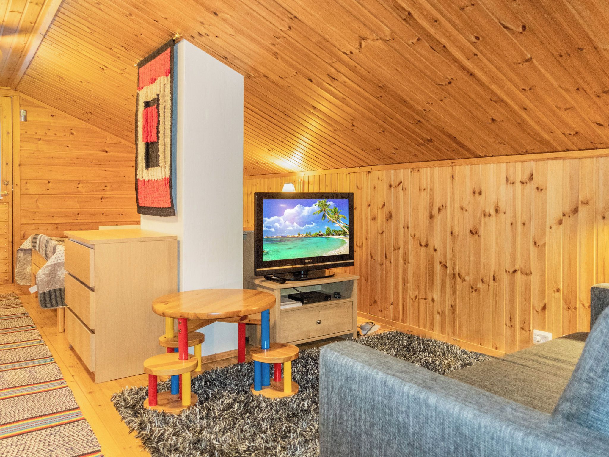 A cozy room with a television, wooden furniture, and a patterned rug.