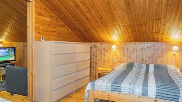 Una habitación de madera con una cama, un televisor y un escritorio.