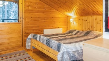 Acogedora habitación tipo cabaña con cama, ventana y lámpara.
