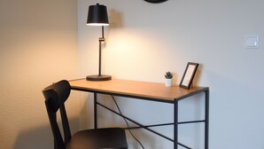 Uma mesa com luminária, cadeira e uma pequena planta.