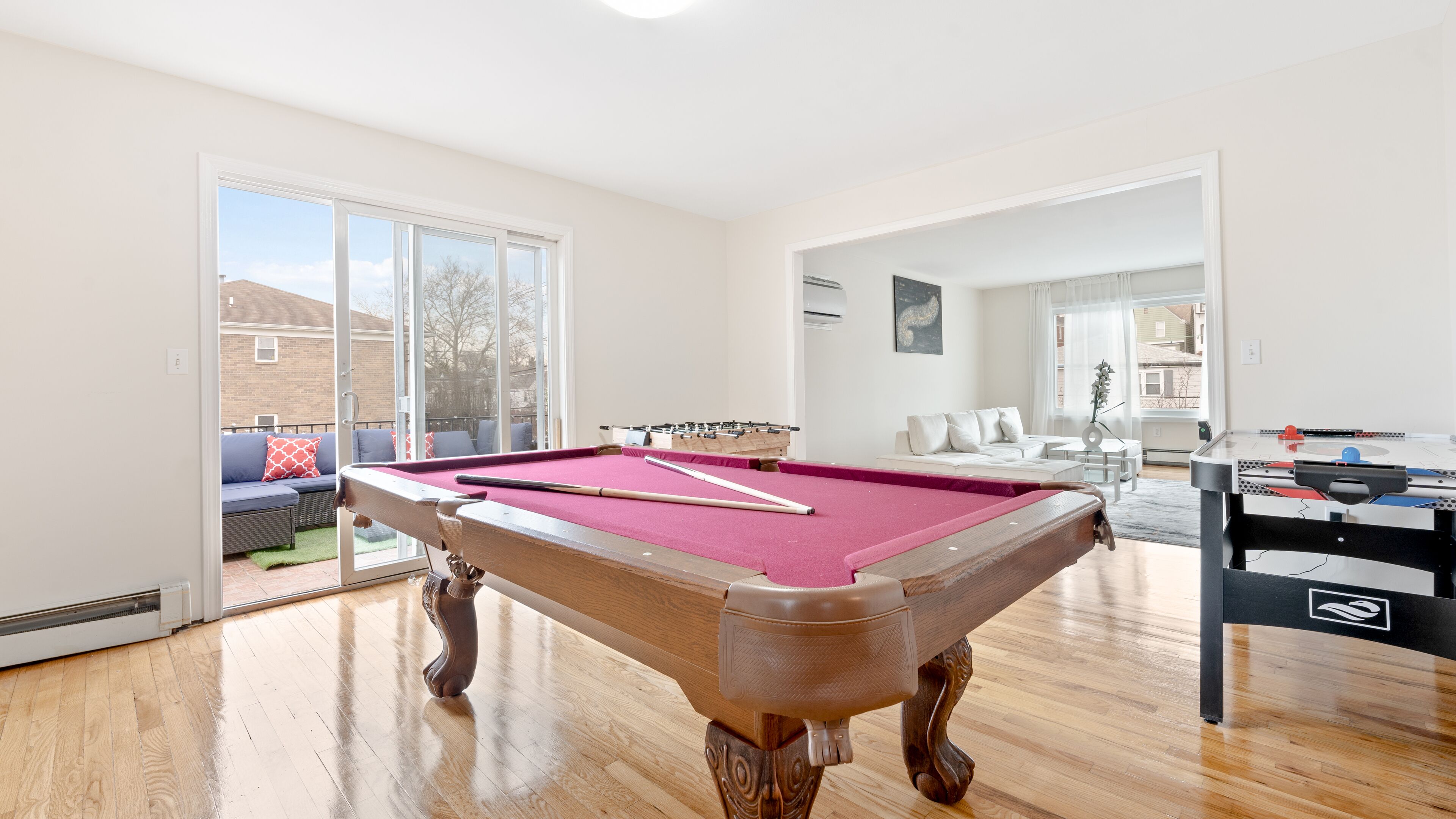 A spacious room with a pool table, a foosball table, and a sofa.