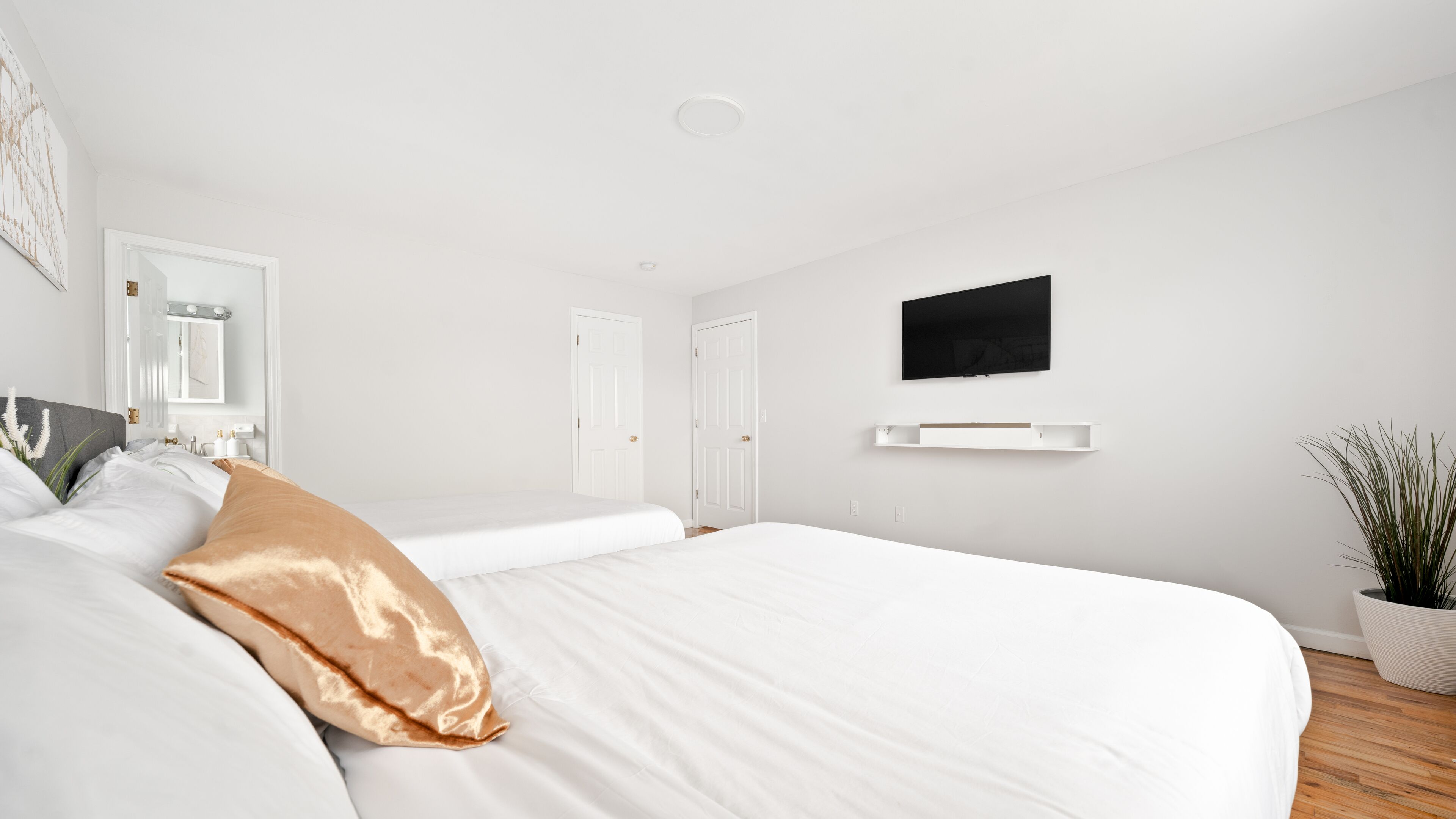 Un dormitorio moderno con una cama grande, un televisor montado y un diseño minimalista.