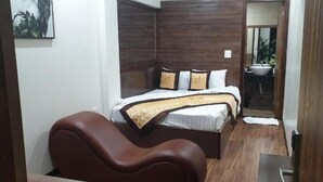 Un dormitorio con cama, una silla y un baño visible a través de una puerta abierta.