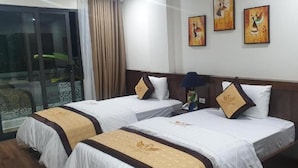 Una habitación de hotel con dos camas, una puerta corrediza al balcón y obras de arte en la pared.