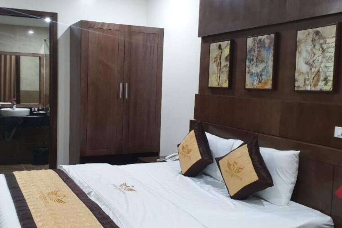 Quarto de hotel com cama, guarda-roupa, casa de banho com espelho e obras de arte na parede.