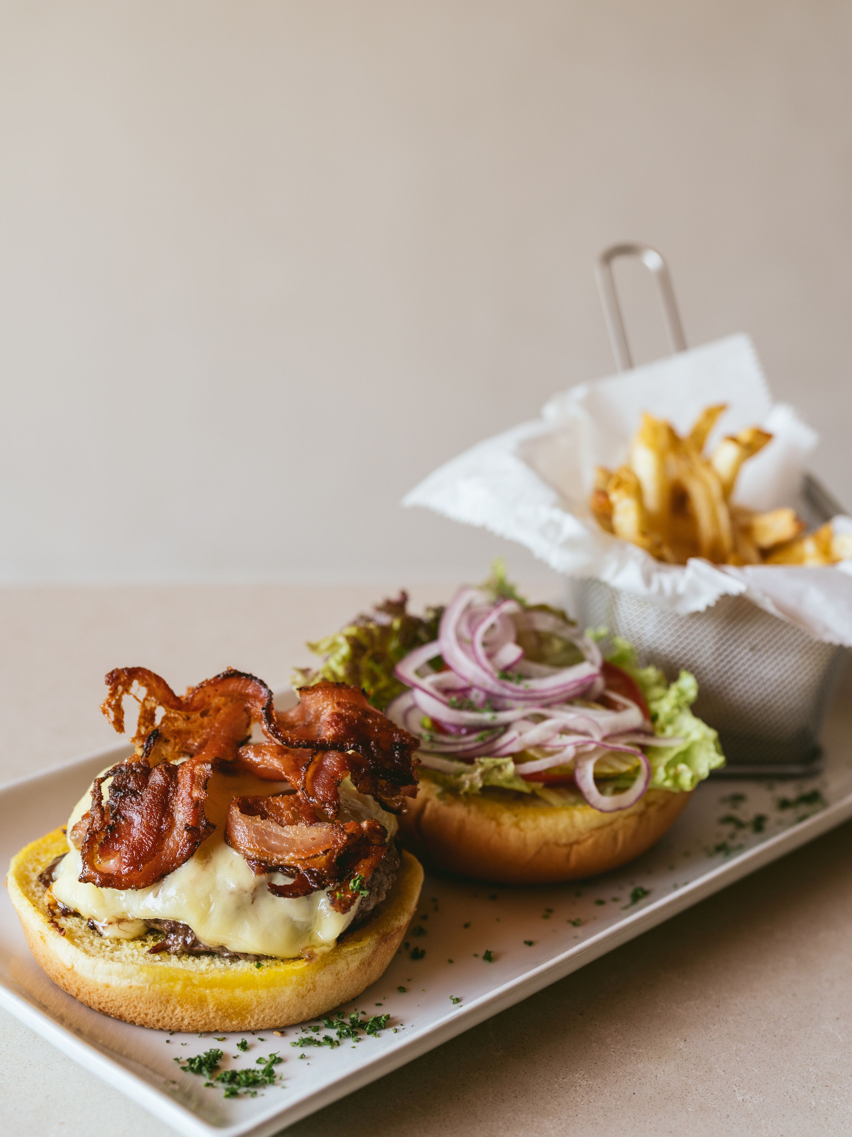 Un sándwich de tocino y queso en pan, acompañado de papas fritas.