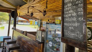 A rustic café with a chalkboard menu listing prices for drinks and snacks.