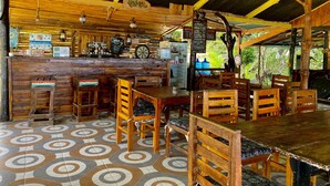 A rustic wooden bar area with a counter, stools, and a refrigerator.