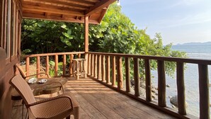 A wooden deck with a railing overlooking a body of water and greenery.