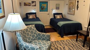 Ein Schlafzimmer mit zwei Betten, einem Sessel, einer Klimaanlage und Wandbildern.