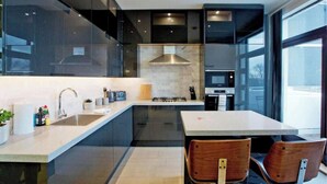 Uma cozinha moderna com uma ilha central, eletrodomésticos de aço inoxidável e janelas amplas.