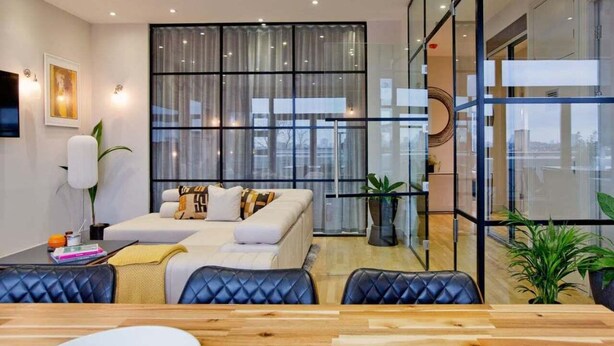 Uma sala de estar moderna com um sofá, uma mesa de jantar e uma janela grande.