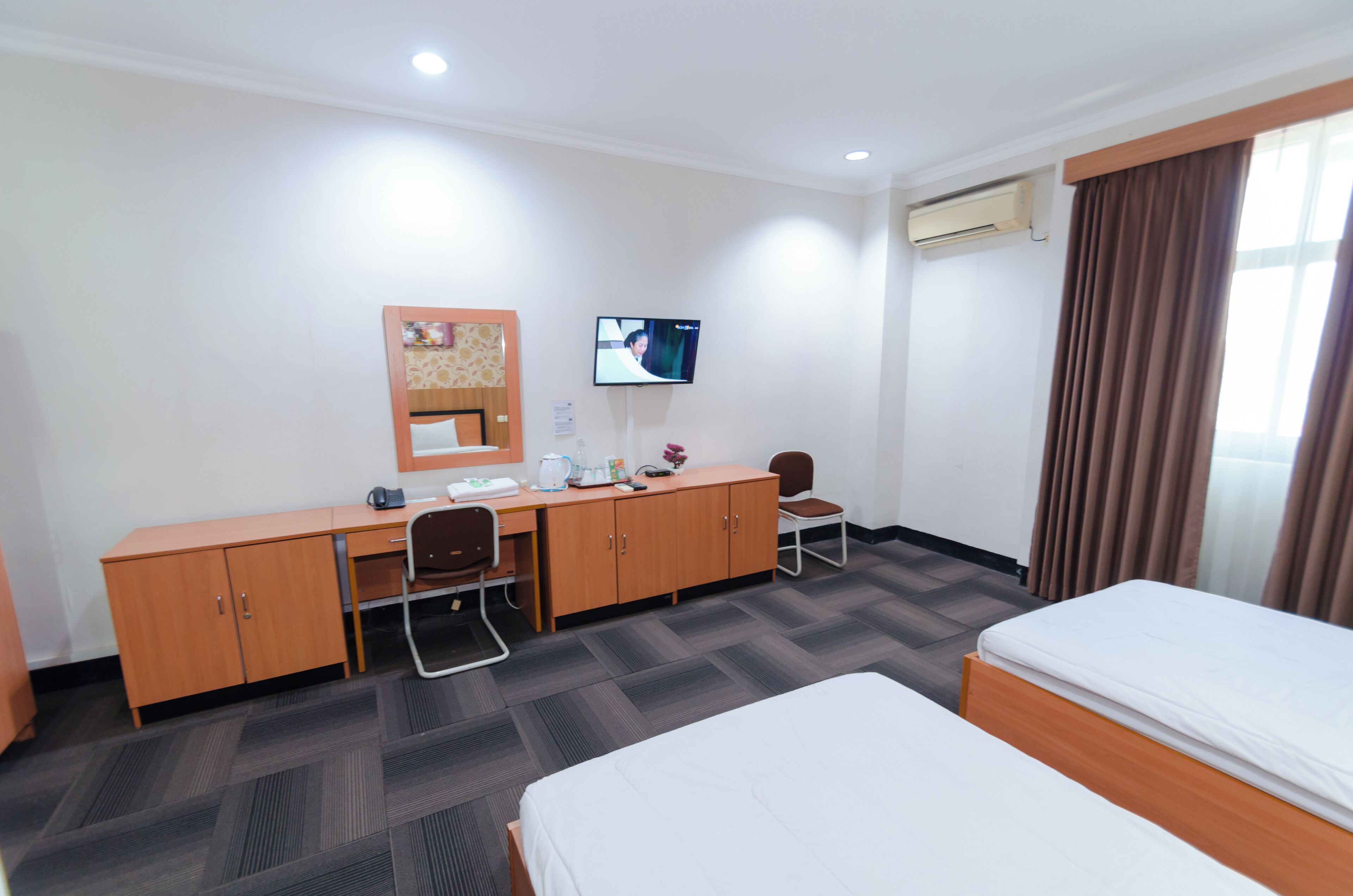 A hotel room with a bed, a desk with a chair, a television, and a wardrobe.