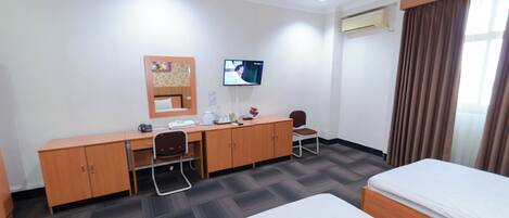 A hotel room with a bed, a desk with a chair, a television, and a wardrobe.