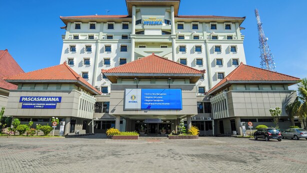 A large building with multiple floors, a central entrance, and a sign indicating it is a government office. - Graha Widya Bhakti at STIESIA Surabaya (Surabaya)