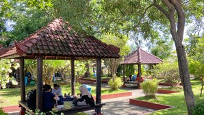 A gazebo with a tiled roof surrounded by lush greenery and a paved walkway. - Graha Widya Bhakti at STIESIA Surabaya (Surabaya)