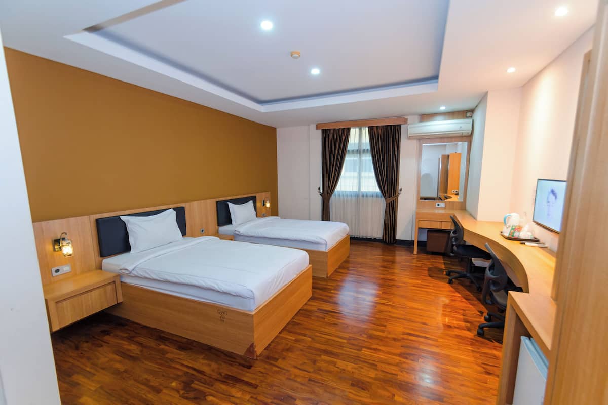 Une chambre d’hôtel avec deux lits, un bureau, une chaise, un miroir et une fenêtre avec des rideaux.
