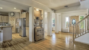 Una cocina amplia con armarios de madera, un refrigerador y una mesa de comedor de madera.