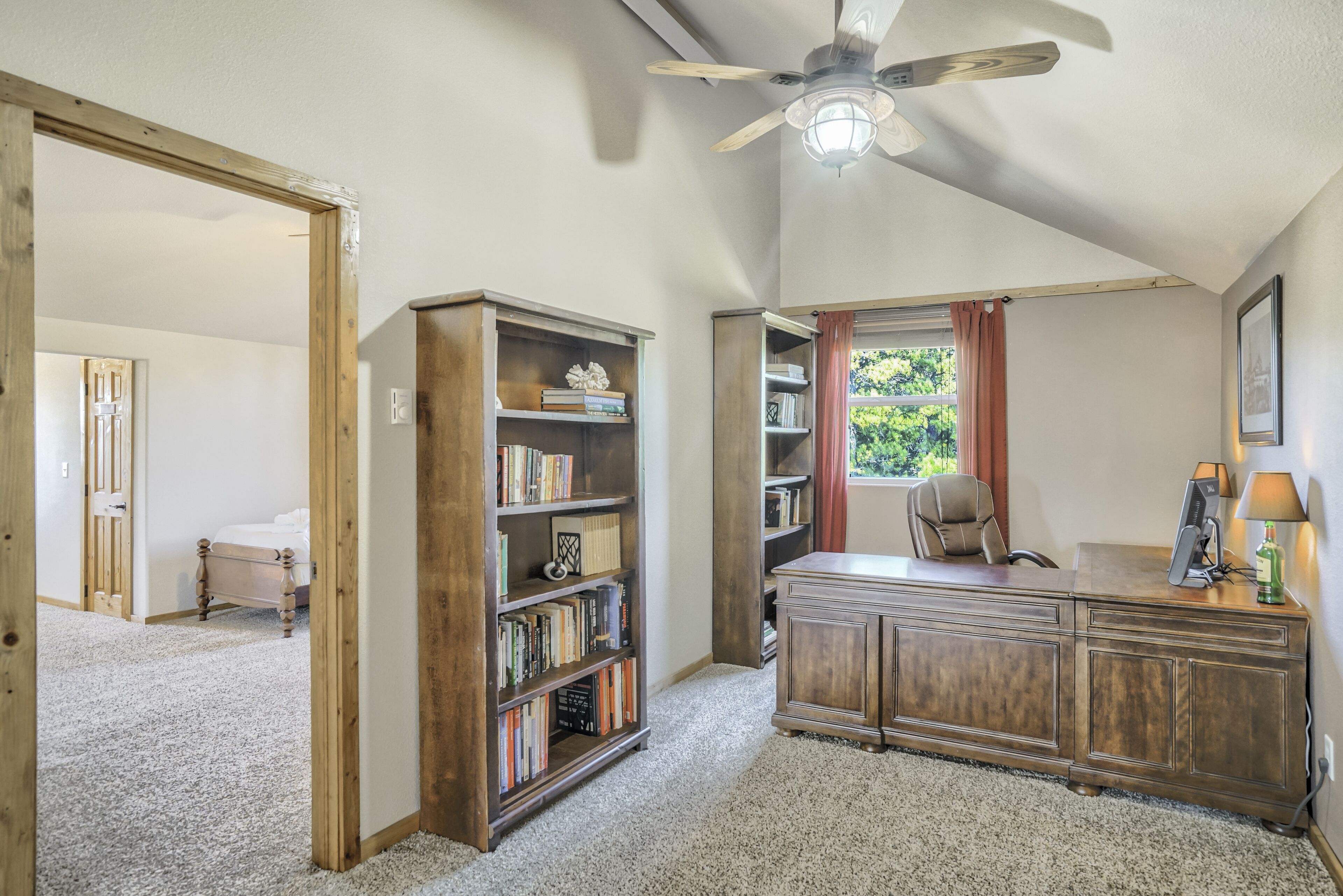 Ein Zimmer mit Schreibtisch, Bücherregal und einem Bett.