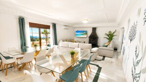 Una sala de estar moderna con una mesa de comedor de vidrio, sofás blancos y una chimenea.