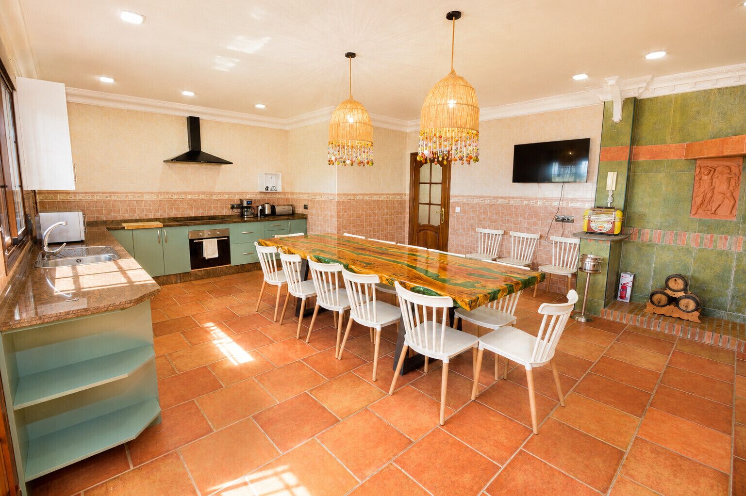 A spacious kitchen with a dining area, a built-in oven, and a TV mounted on the wall.