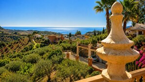 Una villa costera con vistas al mar, viñedos en terrazas y una barandilla de piedra.