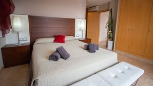 A hotel room with a large bed, two bedside tables with lamps, a wooden wardrobe, and a potted plant. - Tranquil Paradise, Private Pool - only 200m to beach! (El Perelló)