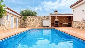 A swimming pool with stone walls and a barbecue area. - Tranquil Paradise, Private Pool - only 200m to beach! (El Perelló)