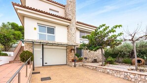 A two-story house with a stone chimney, a garage, and a paved driveway. - Tranquil Paradise, Private Pool - only 200m to beach! (El Perelló)