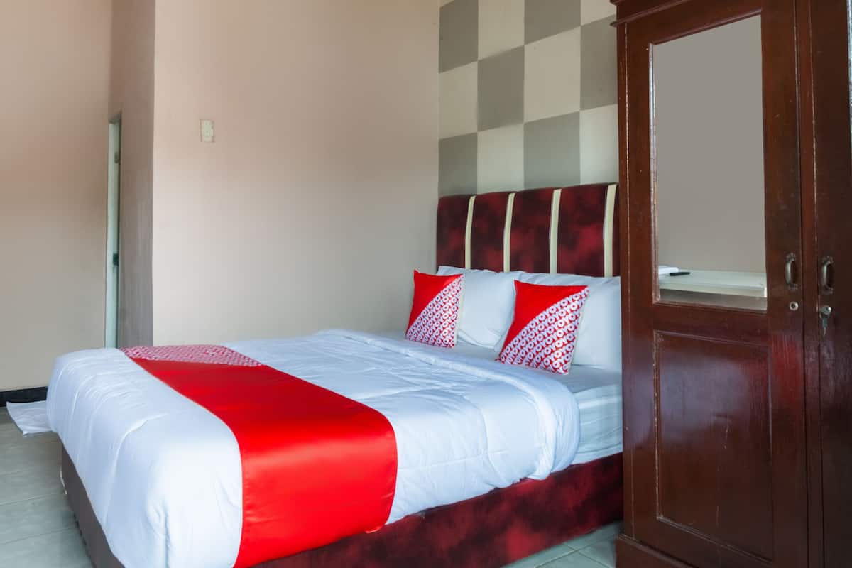 A hotel room with a bed, a wardrobe, and a checkered wall pattern.