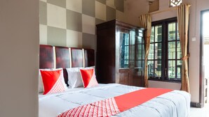 Una habitación de hotel con una cama grande, cabecera de madera y una ventana con cortinas.