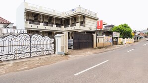 Un edificio residencial de varios pisos con una entrada porticada, un automóvil estacionado y un cartel visible.