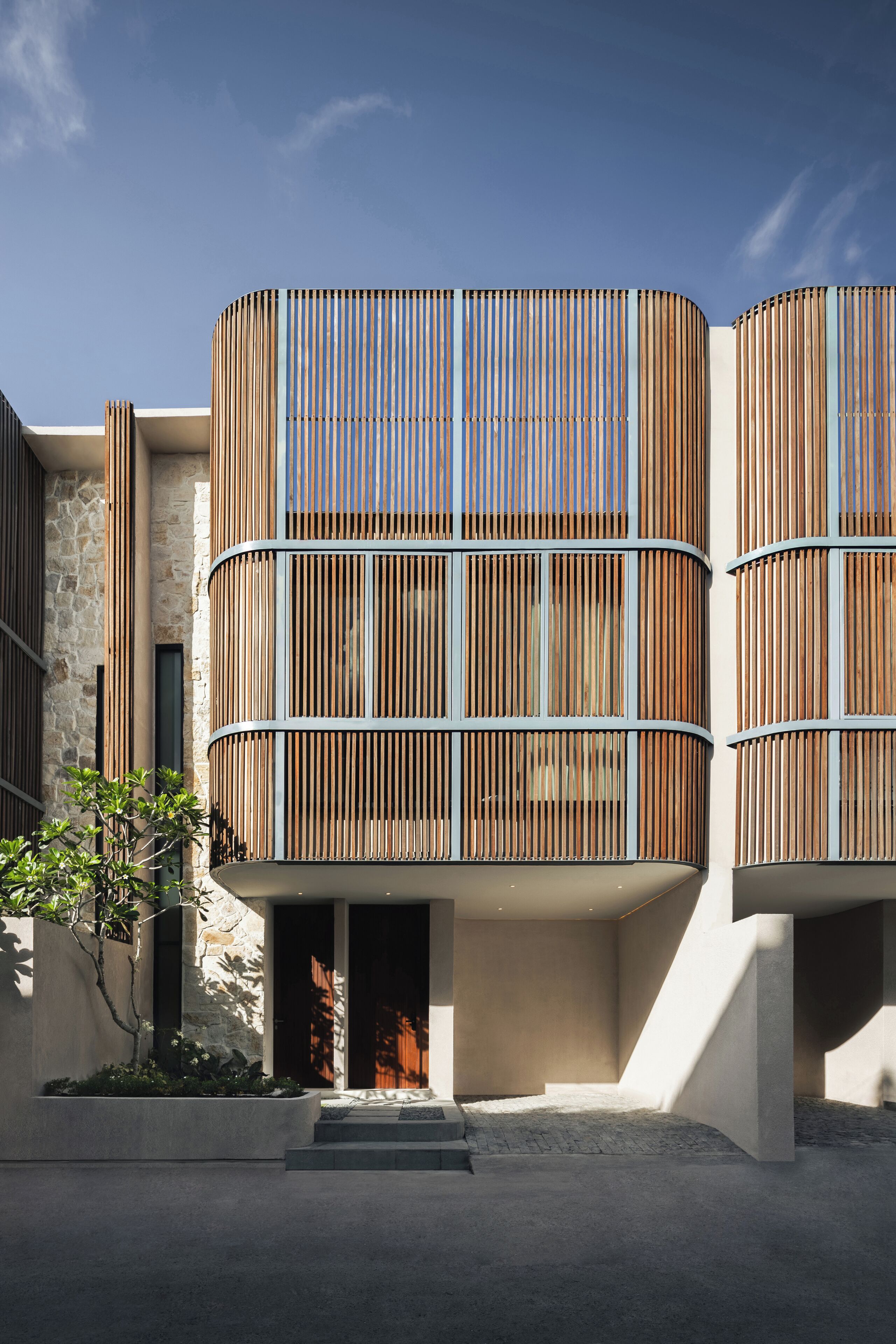 Un edificio moderno con fachada curva, ventanas amplias y base de piedra.