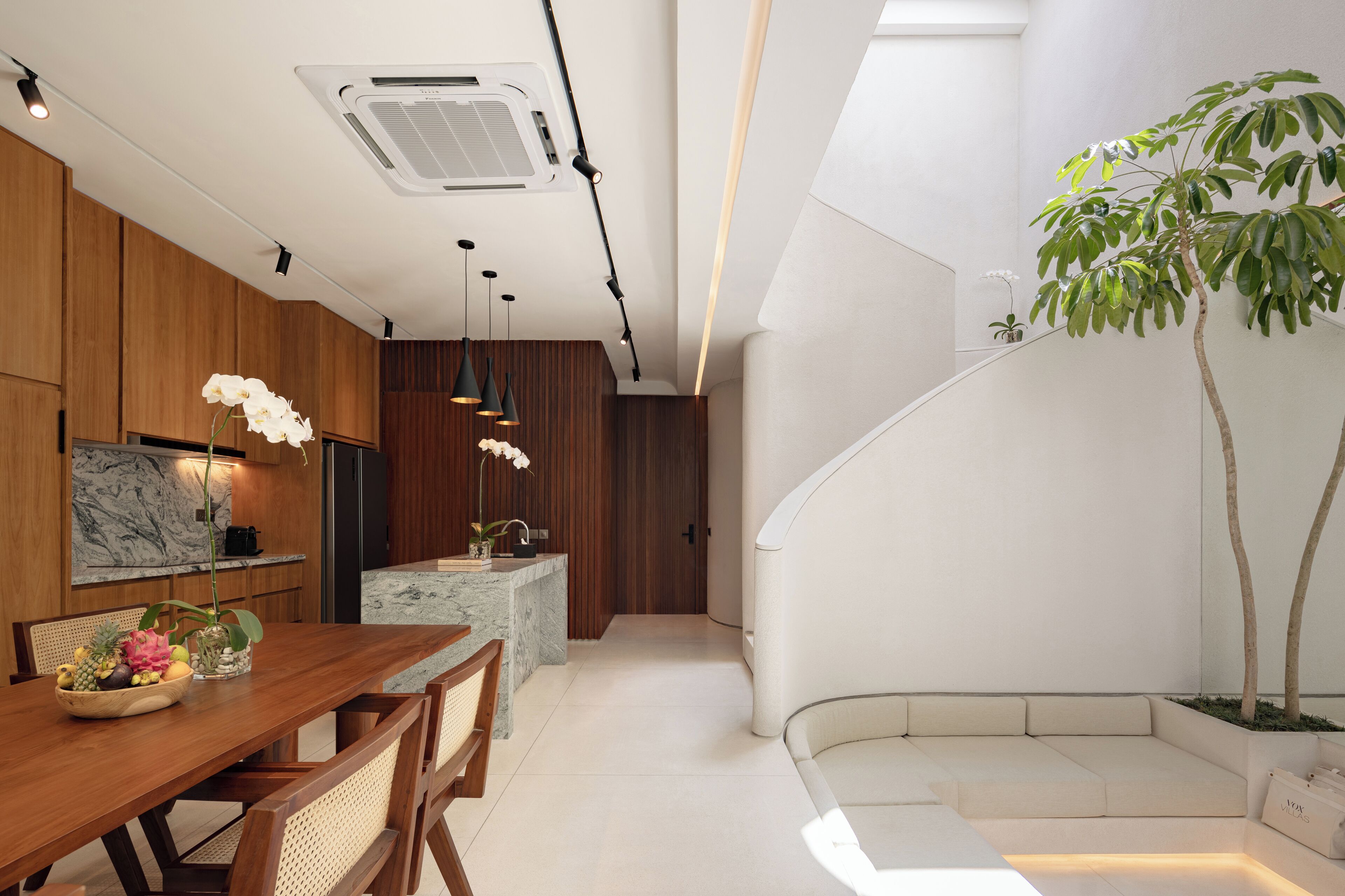 A modern kitchen with wooden cabinets, a marble countertop, and pendant lighting.