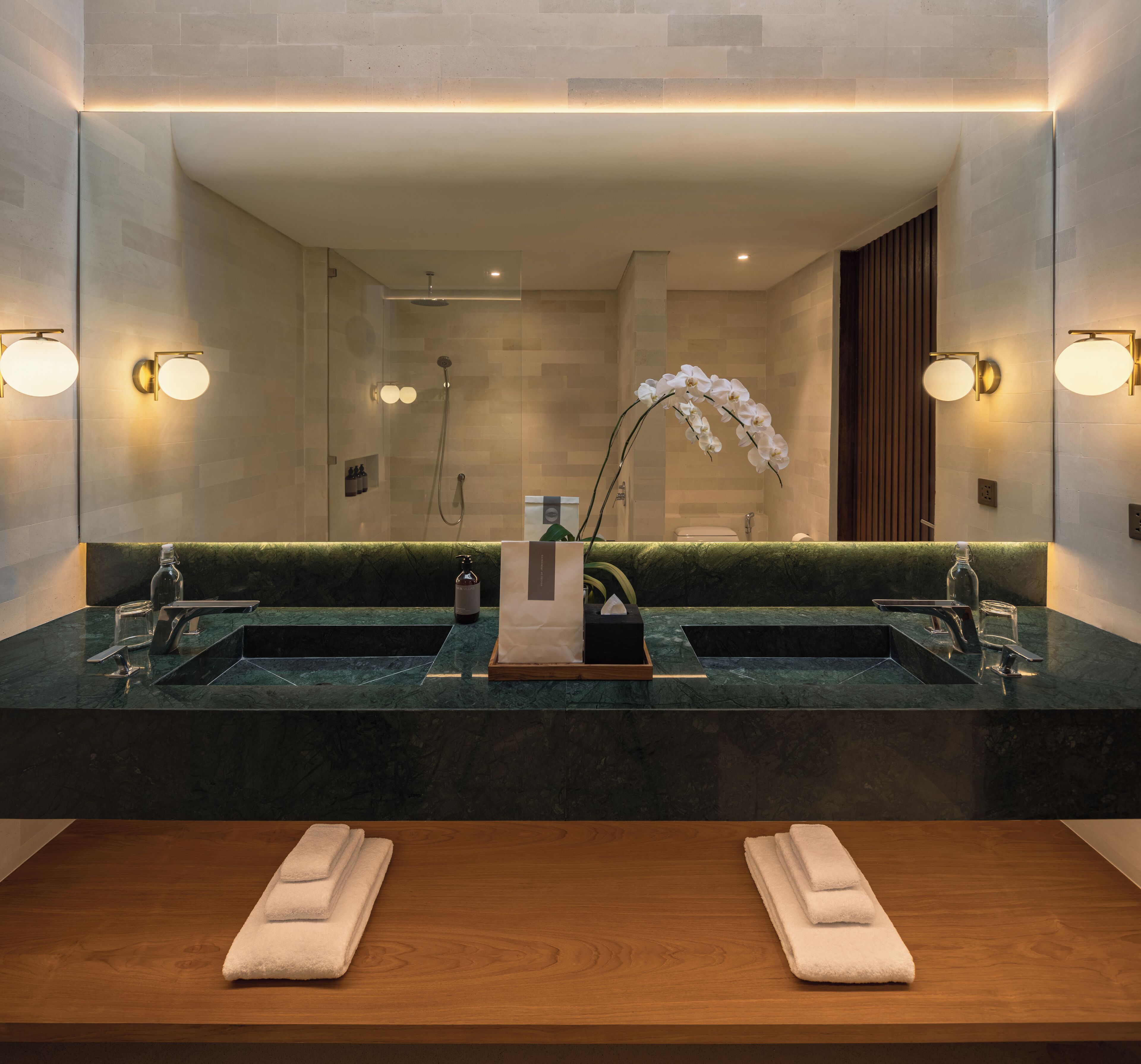 A modern bathroom with two sinks, a large mirror, and a shower.