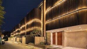 Um edifício moderno com fachada curva, iluminado por luzes quentes.