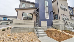 A modern multi-story residential building with concrete steps, a metal railing, and a landscaped area with pebbles and small shrubs. - Rio Grande (Colorado Springs)