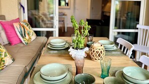 A dining table set with plates, bowls, and a vase with green plants. - The Garden by the Sea (Saint-Raphaël)
