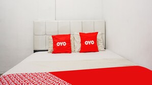 A bed with a white headboard and two red pillows with the word "OYO" on them. - Hotel O Bintang Residence (Jakarta)