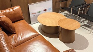Un área de descanso moderna con asientos de cuero, una mesa de madera y sillas de metal.