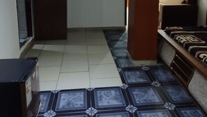 Ein Zimmer mit Fliesenboden, einem Kleiderschrank, einer Couch und einem Bett.