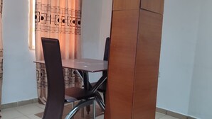 Ein Zimmer mit Esstisch, Stühlen, einer Klimaanlage und einem Vorhang mit Muster.