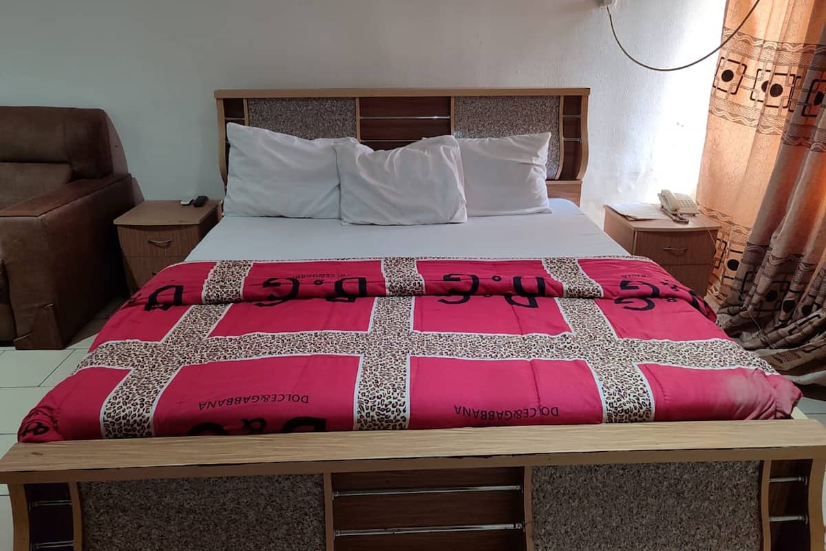 A bedroom with a wooden bed frame, white bedding, and a red and white patterned blanket.