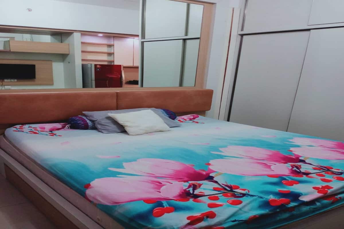 A bedroom with a bed, a television mounted on the wall, and a wardrobe.