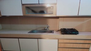 A compact kitchen with a microwave, a sink, and a compact stove. - OYO 93543 Belmount Residence Near SILOAM CLINIC MERUYA (Jakarta)